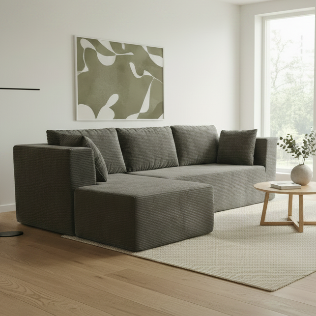 Gray sectional sofa in a showroom setting with other furniture in the background.