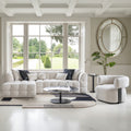 Modern living room with a white sectional sofa, round coffee table, and armchair.