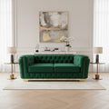 Green velvet sofa on a black marble floor with 'Velora living' branding.